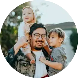 Glückliche Familie, die sich über die Mietwagenoptionen freut Lächelnder Mann, der zwei kleine Kinder auf seinen Schultern im Freien trägt.