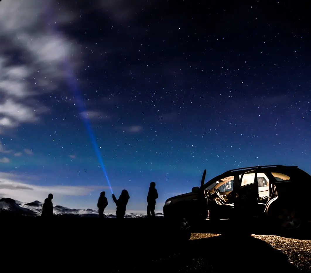 Silhouetten von Menschen und zwei 4x4-SUVs vor einem dramatischen isländischen Sonnenuntergang, die Abenteuer und Erkundung in anspruchsvollem Gelände betonen.