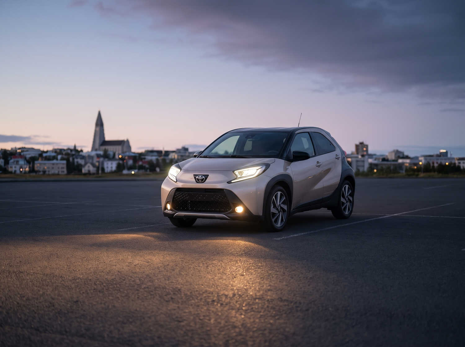 Leuchtend orangefarbener Toyota Aygo mit Automatikgetriebe, ideal für 4 Personen, kompakt und effizient für Fahrten in isländischen Städten.