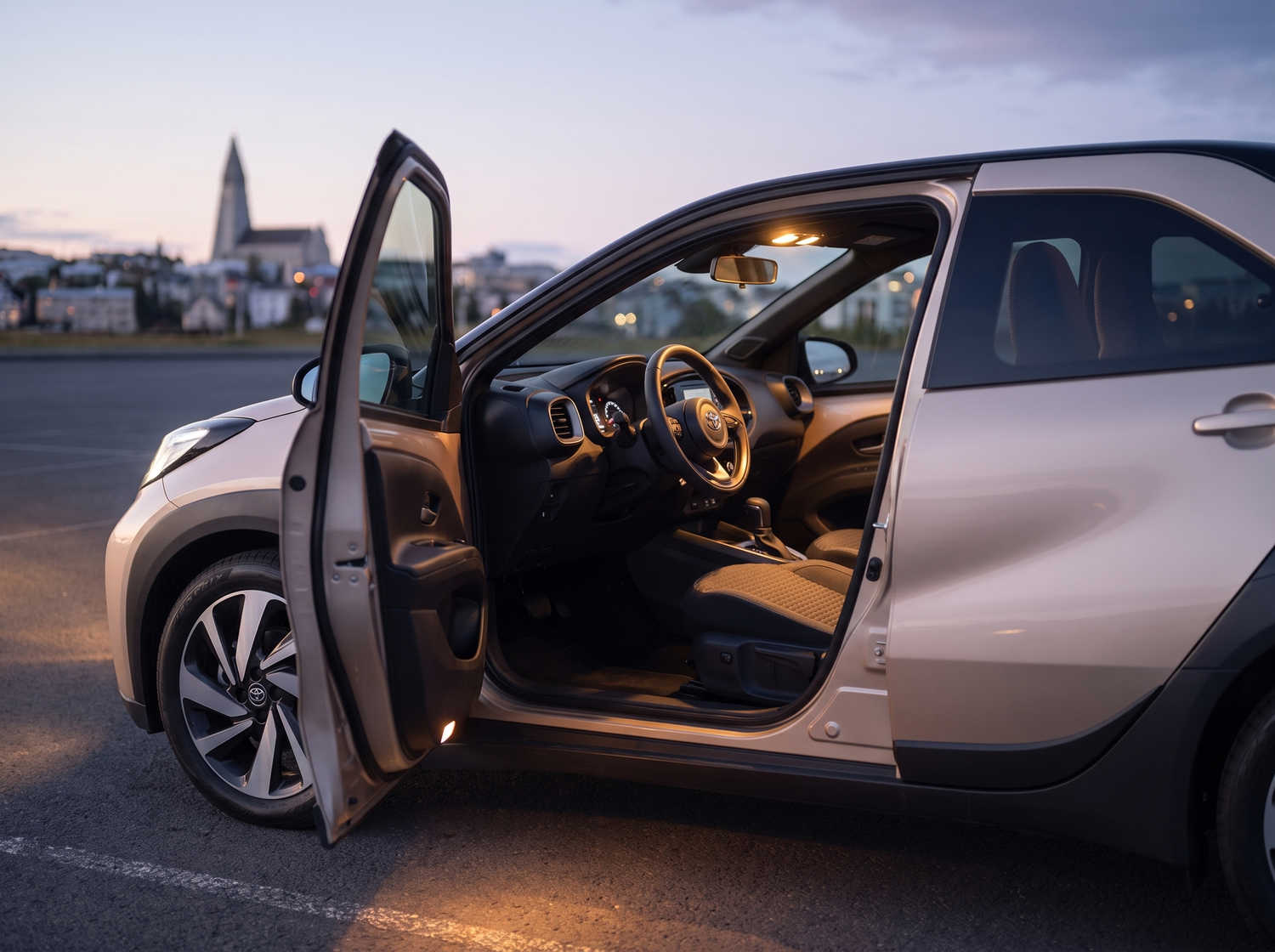Leuchtend orangefarbener Toyota Aygo mit Automatikgetriebe, ideal für 4 Personen, kompakt und effizient für Fahrten in isländischen Städten.