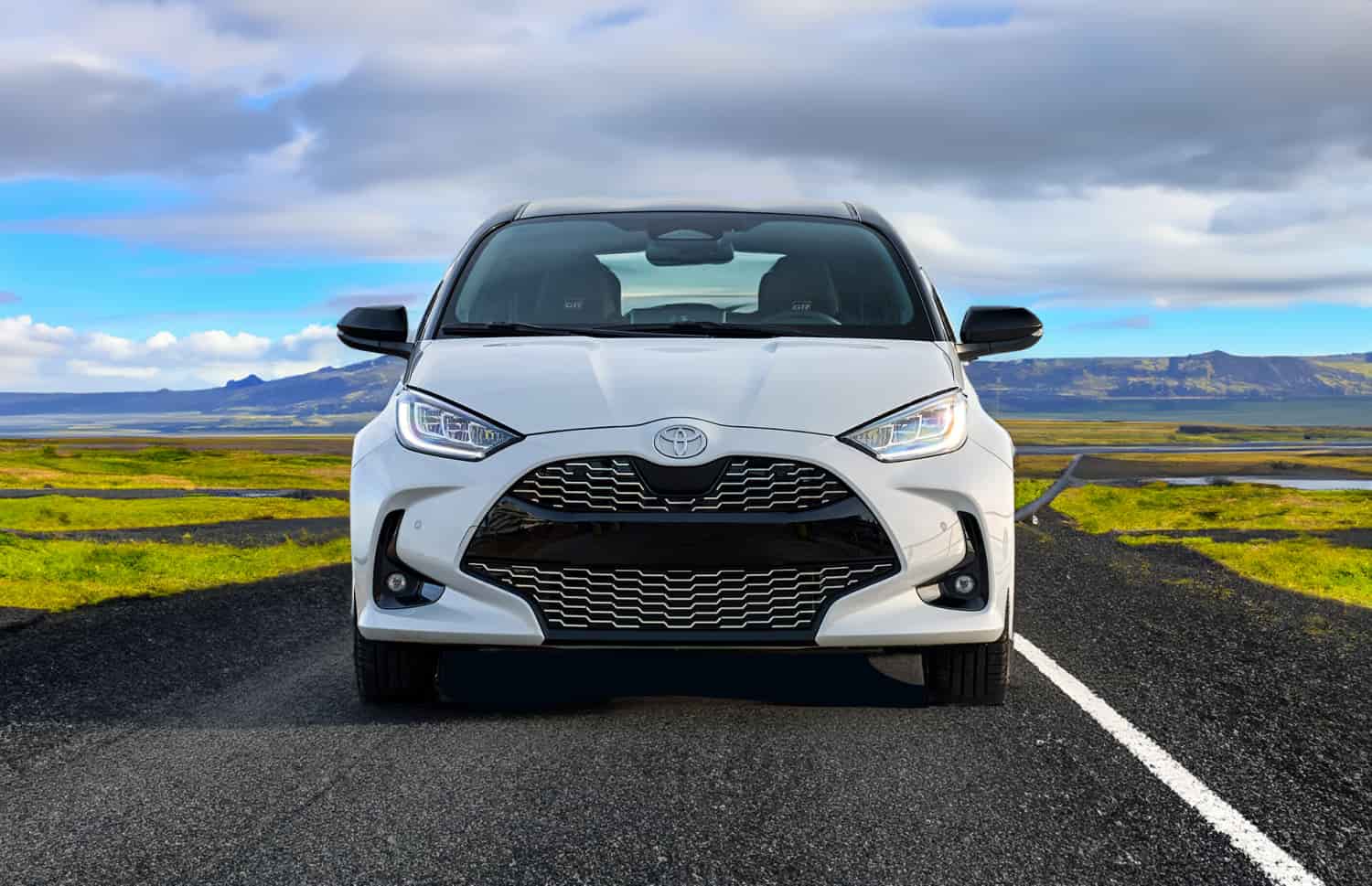 Roter Toyota Yaris Hybrid mit Automatikgetriebe, 5 Sitze, GPS, Rückfahrkamera und Platz für 2 Gepäckstücke – ideal für Reisen durch Island.