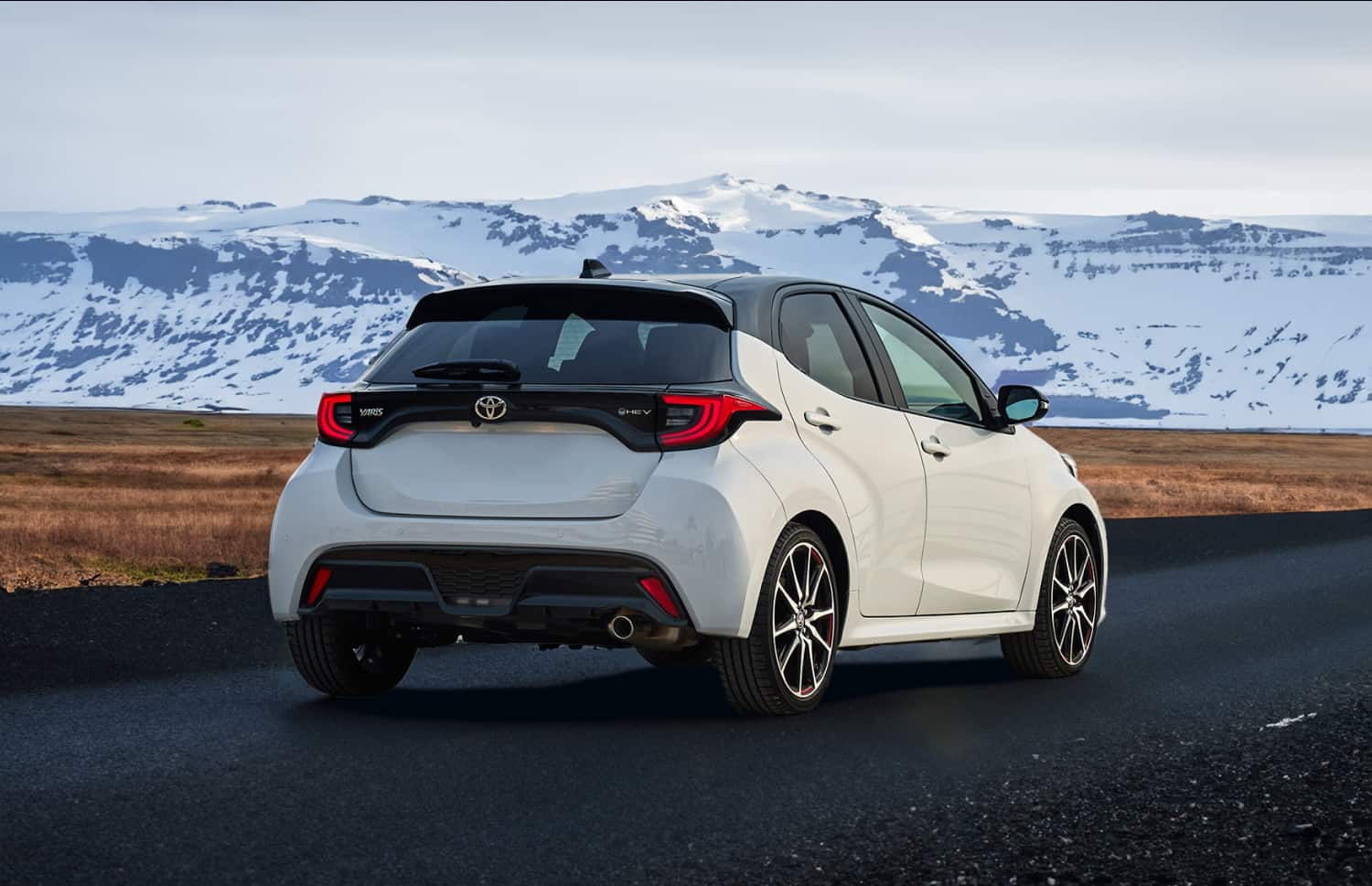 Roter Toyota Yaris Hybrid mit Automatikgetriebe, 5 Sitze, GPS, Rückfahrkamera und Platz für 2 Gepäckstücke – ideal für Reisen durch Island.